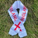 White England scarf with red text and cross symbol on grass