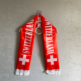 Red scarf with 'Switzerland' text and white cross, hanging on a gray background